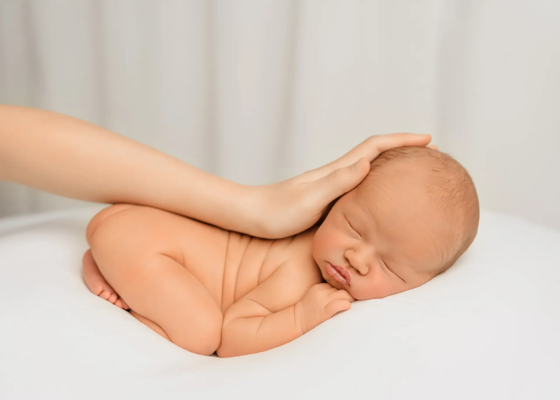 Sleeping newborn with mother's hand gently resting on head - newborn photography Surrey