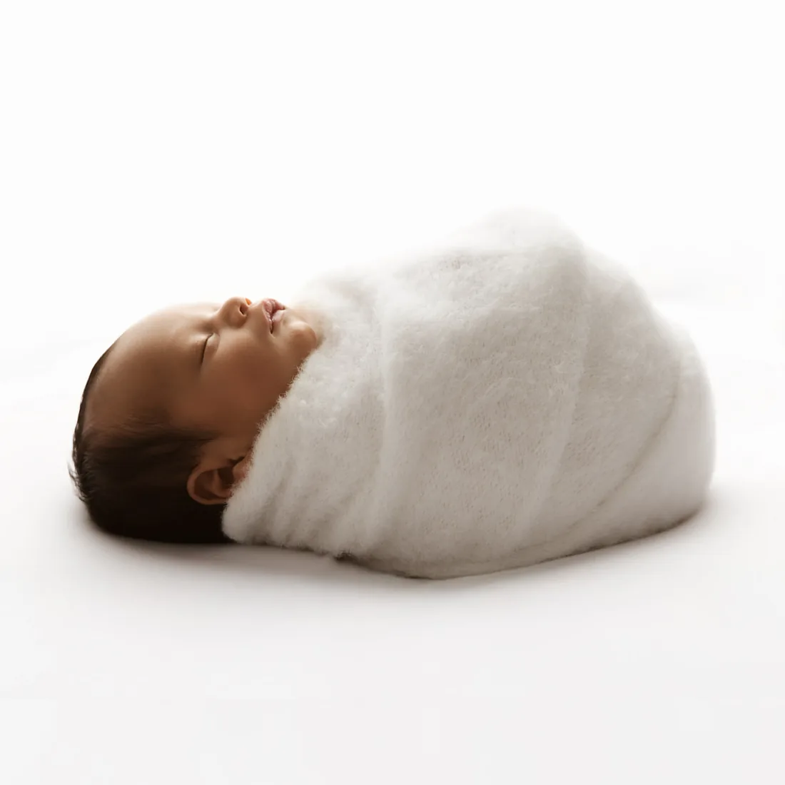 Sleeping newborn swaddled in white knit wrap on white background - newborn photoshoot Kingston upon Thames